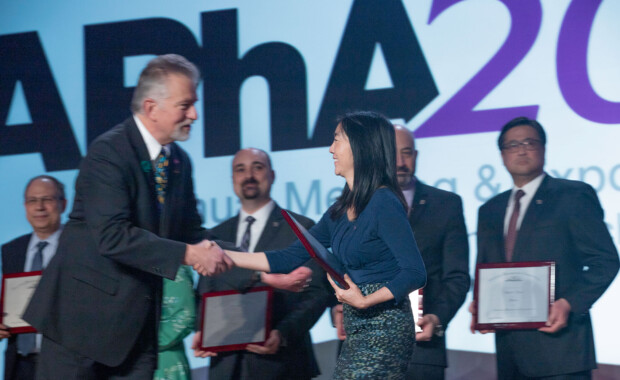 Michelle Chui shaking hands with an APhA leadership staff and receiving a plaque