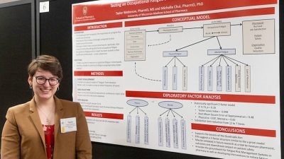 Taylor Watterson standing next to a poster presenting her research