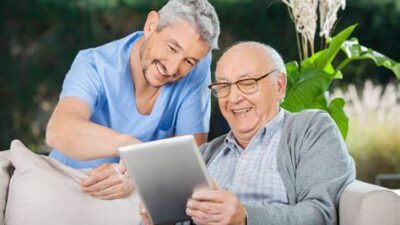 smiling younger man helping smiling older man with tablet