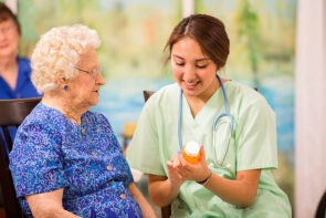 Latin descent female nurse or doctor explains dosage of prescription to a senior woman patient.  Home or clinic setting.  Woman is over 100 years old!