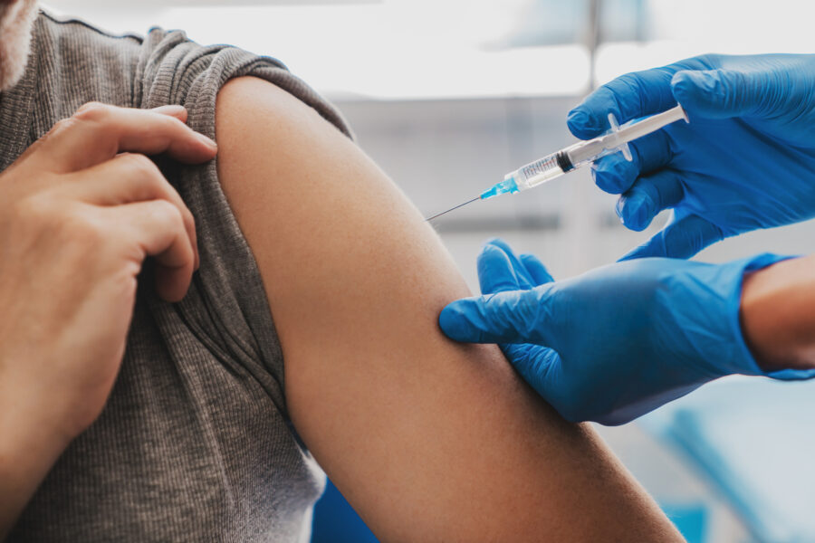 gloved hands giving a patient an injection in bicept