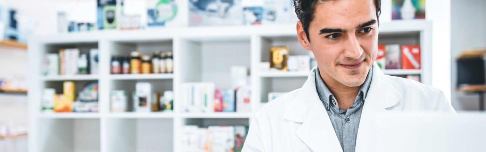 young male pharmacist working at counter