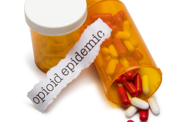 pills and pill bottles with slip of paper with the words opioid epidemic on it