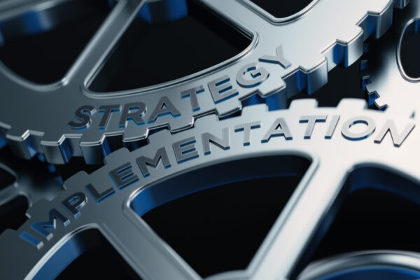 two gears interconnecting with the words strategy and implementation