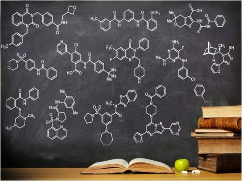 Blackboard with chalk drawing of chemical structures and a pile of books and an apple sitting in front of it