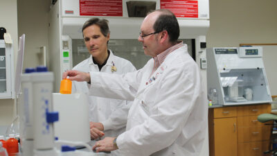 Dr. Edmund Elder and Dr. Mark Sacchetti working together in a pharmaceutical lab
