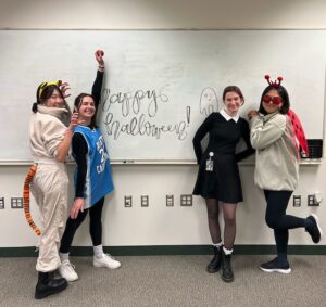 Hong Research members wearing costumes next to a white board reading "Happy Halloween"