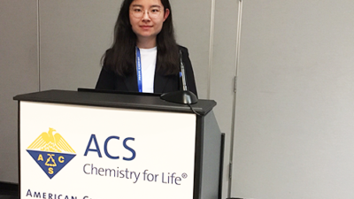 Ao Wang standing behind a podium labeled with ACS Chemistry for Life