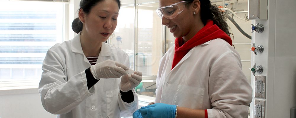 Dr. Jiayang Jiang and Arielis Estevez wearing white lab coats in a pharmaceutical lab