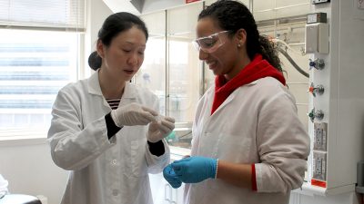 Dr. Jiayang Jiang and Arielis Estevez wearing white lab coats in a pharmaceutical lab