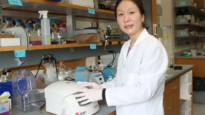 Dr. Jiayang Jiang wearing a lab coat in a pharmaceutical lab