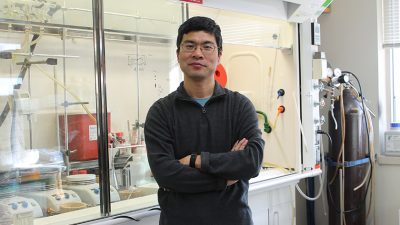 Weiping Tang posing with arms-crossed in a pharmaceutical lab