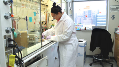 Female student with lab gear on working in pharmaceutical lab