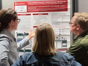 Paula discusses a recent research project with visitors at a poster session