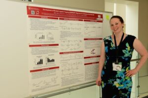 Jillian Kyzer standing with her printed research for the MIKIW conference
