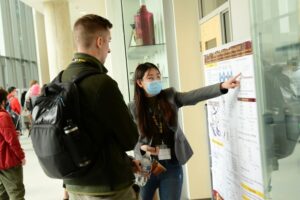 A researcher explaining her printed study to a student at the MIKIW conference