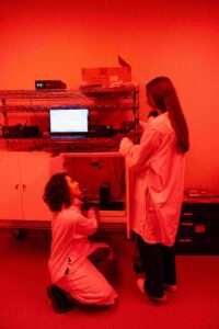 two lab members working in a red lit room