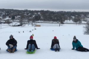 Wenthur lab members sitting on sleds on a snow-covered hill