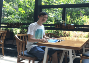 Chengyu Liu sitting at a table in front of a window