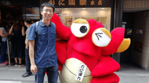 Xin Yao standing next to a large stuffed creature