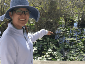 Yue Gui standing in a garden with a hat on