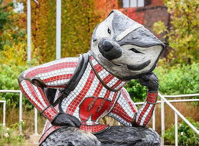 Bucky Badger statue sits in the Thinker pose, looking pensive