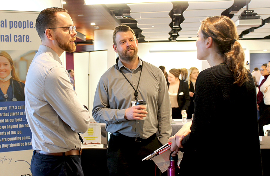 A third year student visiting a booth at the career fair chats with representatives