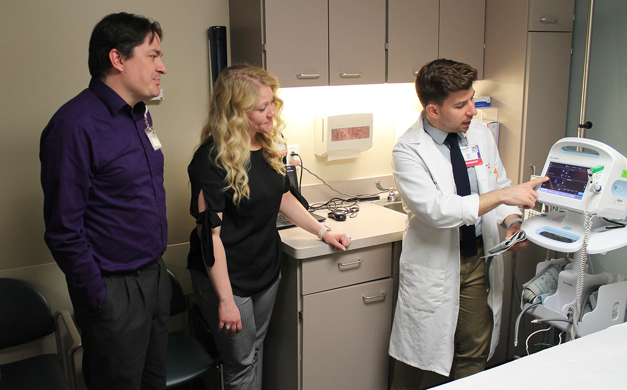 A clinical instructor demonstrates to students how to use a vital signs monitoring device