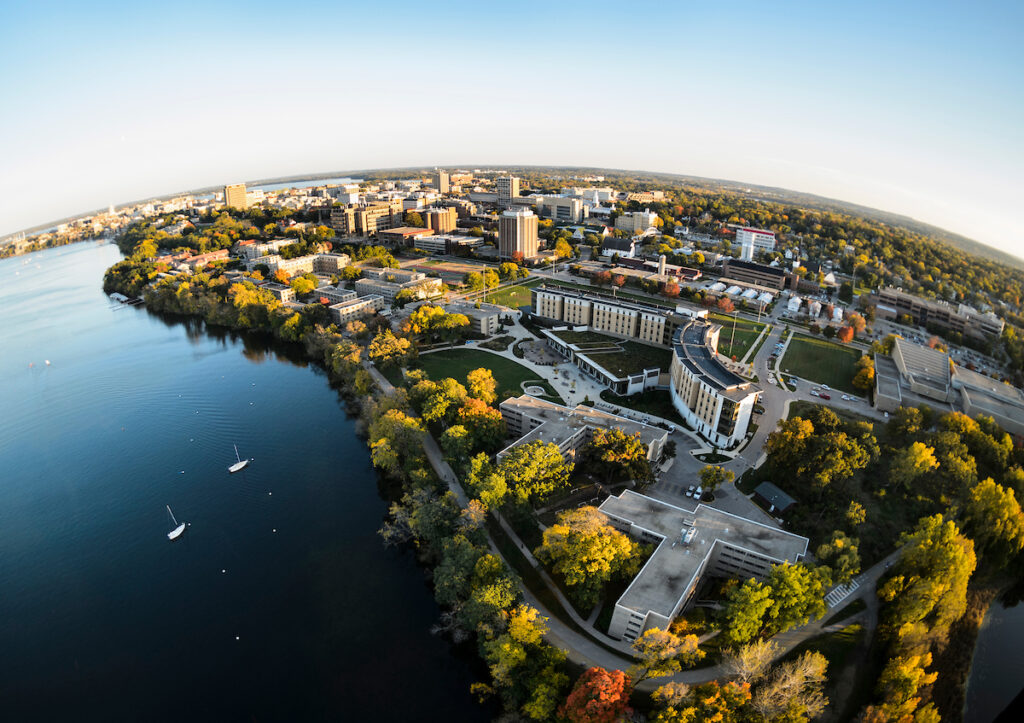 Aerial view of UW-Madison's central campus and Lake Mendota, with colorful autumn leaves and blue sky. Photo by Jeff Miller.