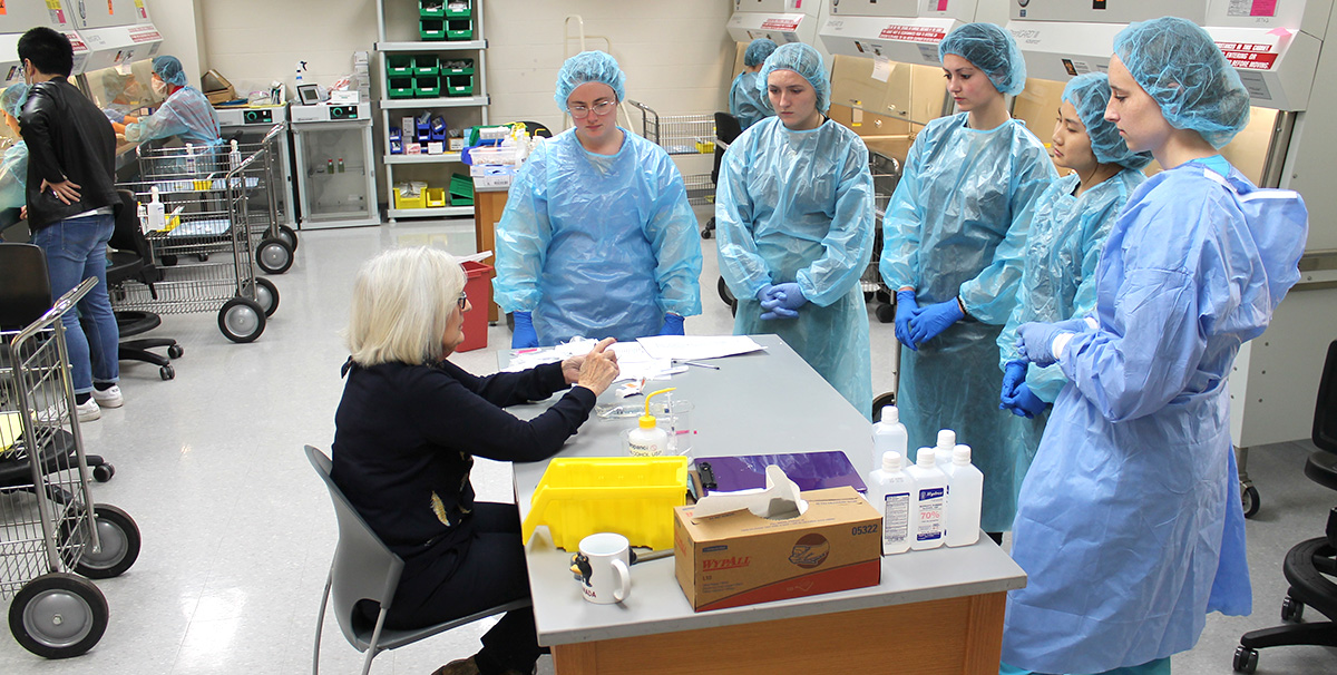 Pharmacy students observe a demonstration before starting their sterile compounding lab assingnment.