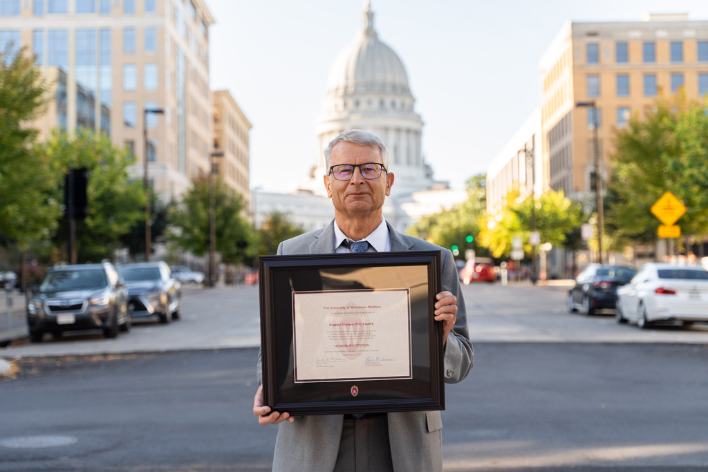 Evgenyi Shalaev holds his award with the Wisconsin capitol building behind her