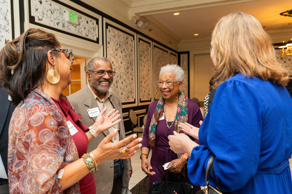 Yolanda Tolson speaks with a group of excited and smiling attendees.