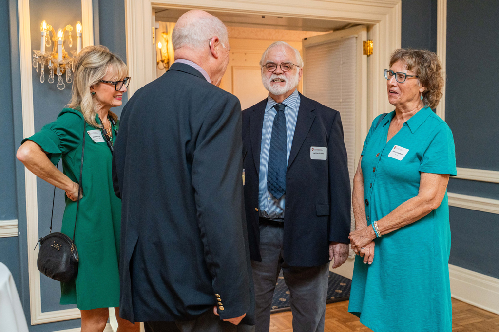 Beth Martin, Arthur Schuna, and two other attendees speak together and smile