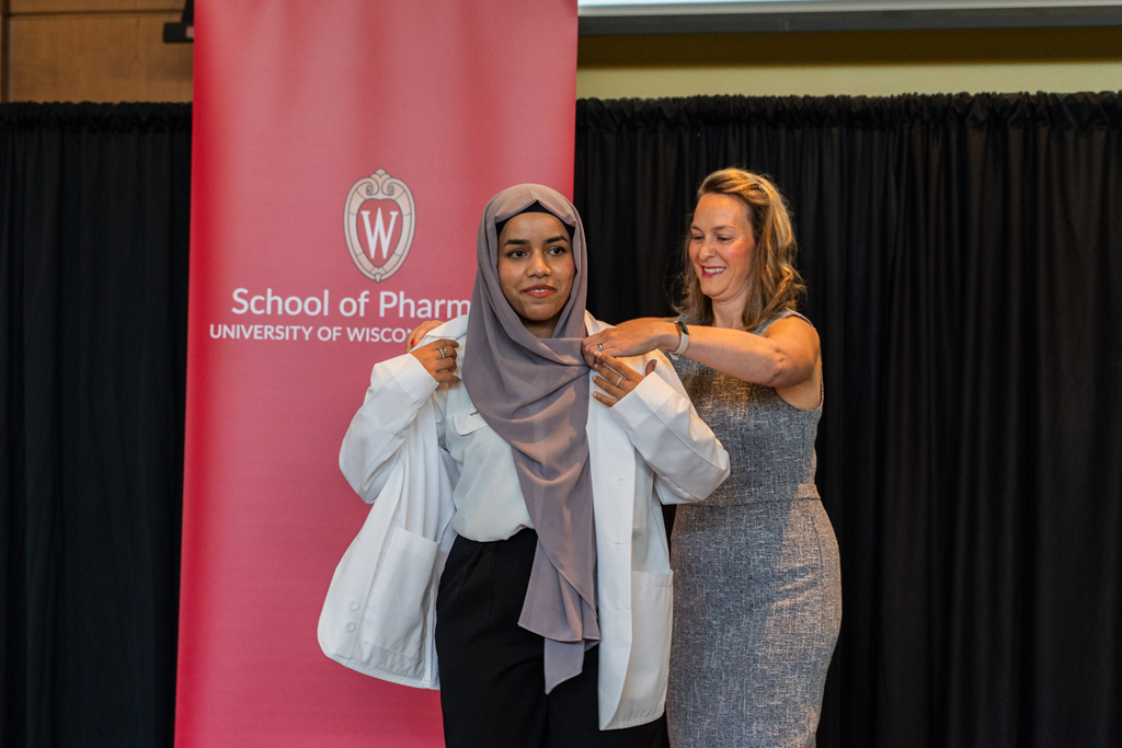 A student receives her white coat from Kate Rotzenberg