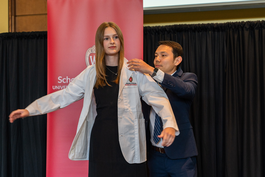 A student receives her white coat from Sean Lim