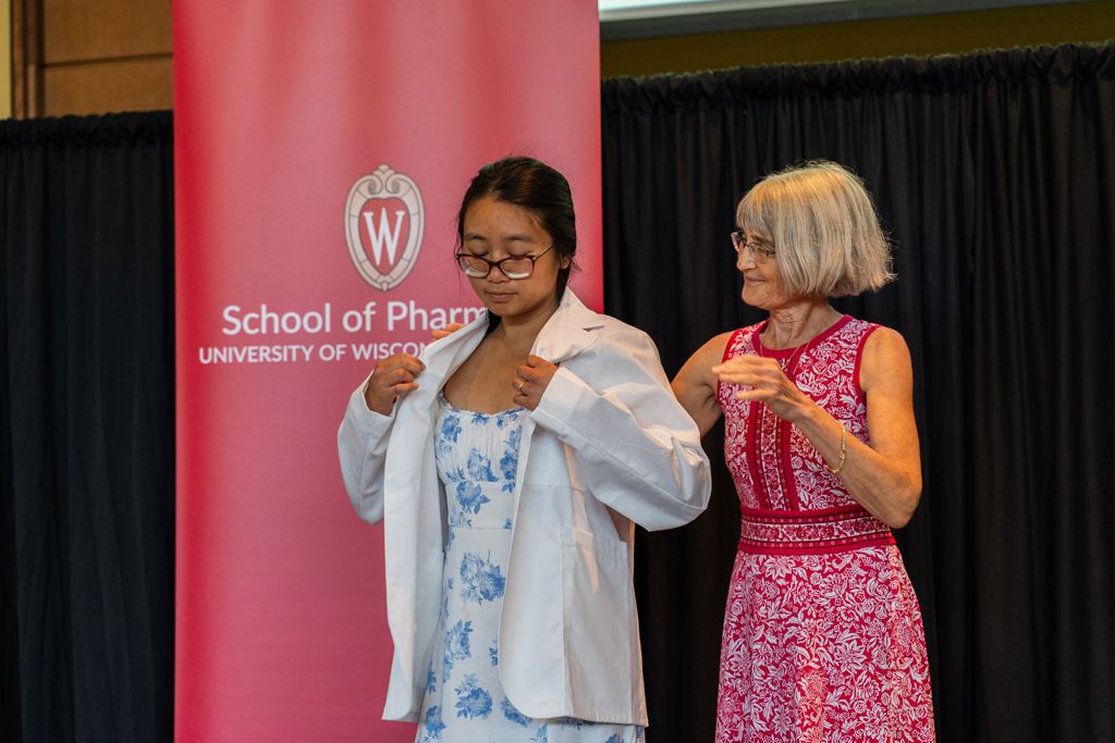 A student receives her white coat from Mara Kieser