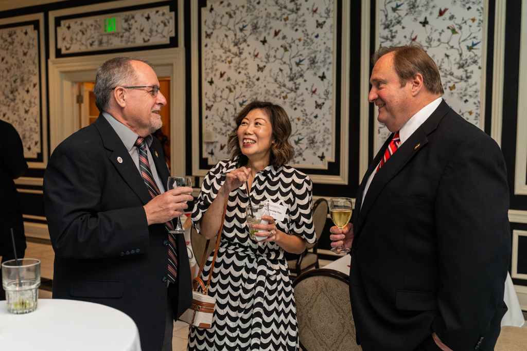 Dean Steve Swanson and Mel de Villiers and a female attendee have a smiling conversation.