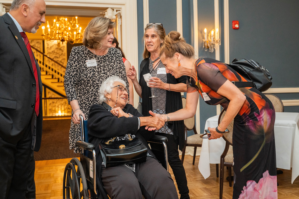 Harry Sharata speaks with attending family members and friends, including an older woman in a wheelchair