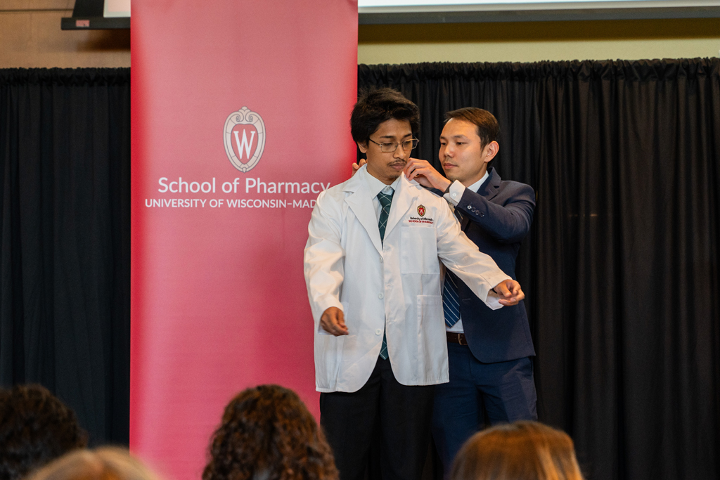 A student receives his white coat from Sean Lim