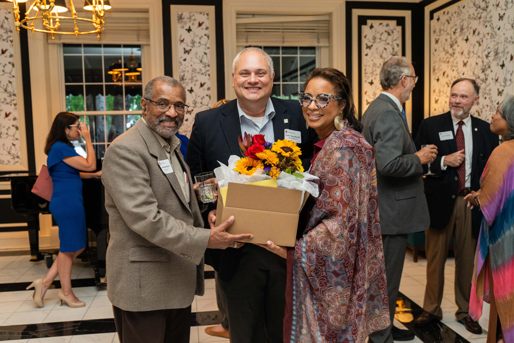 Yolanda Tolson poses with a box of flowers and two gentlemen.