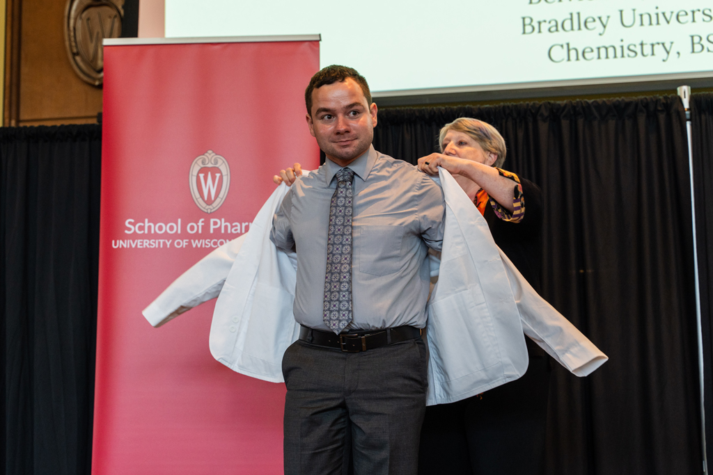 A student receives his white coat from Karen Kopacek