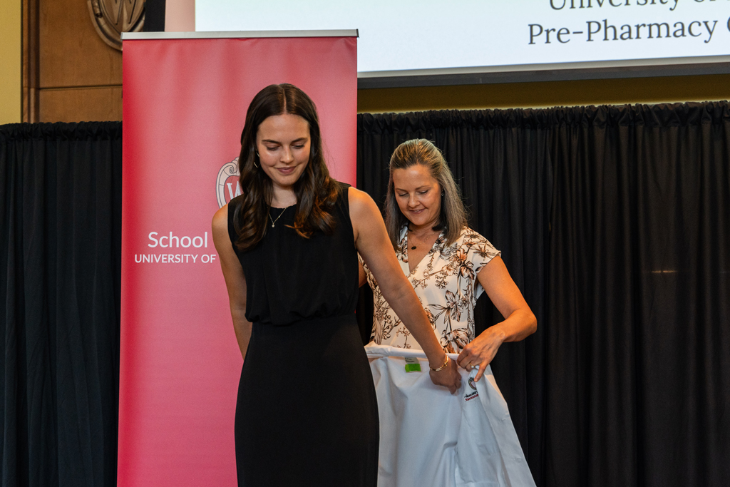 A student receives her white coat from Kate Rotzenberg