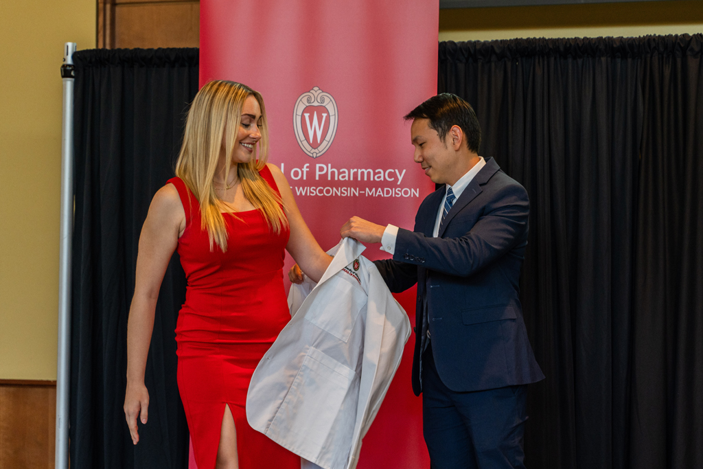 A student receives her white coat from Sean Lim