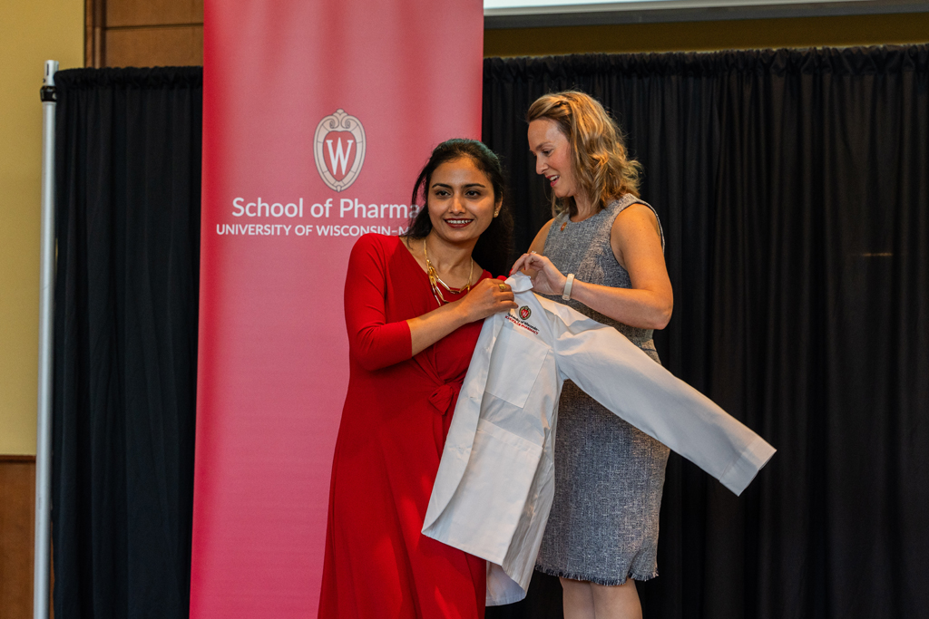 A student receives her white coat from Kate Rotzenberg