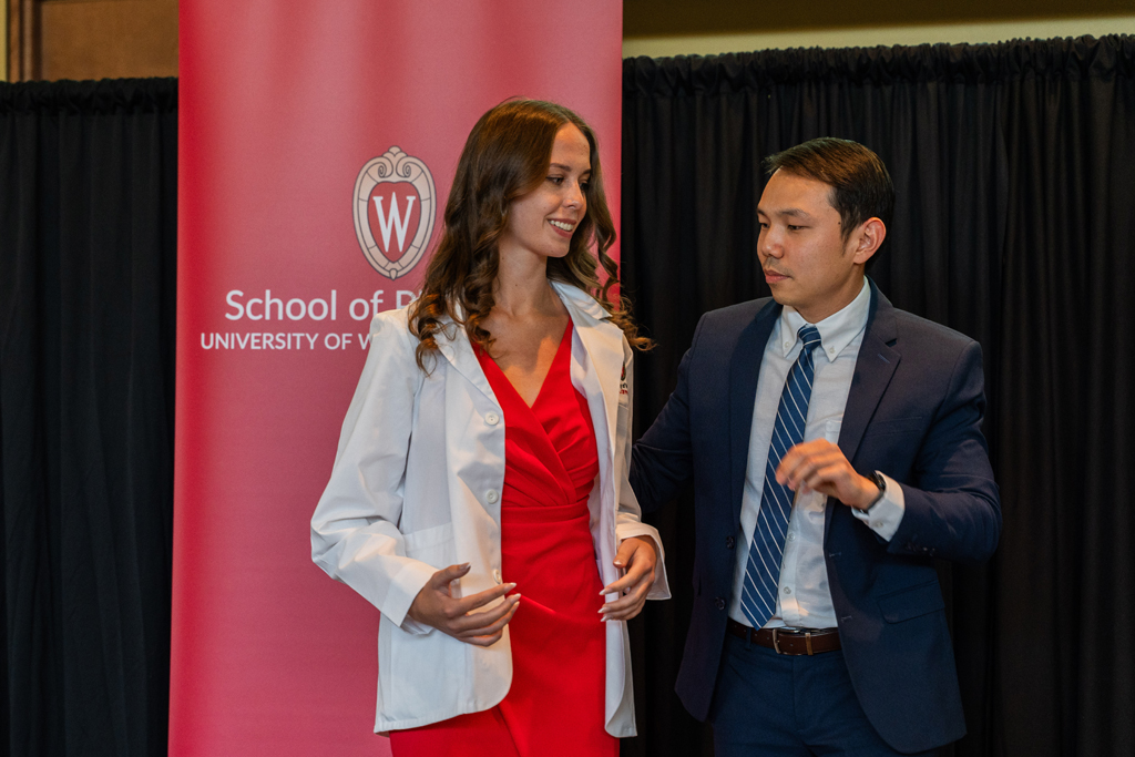 A student receives her white coat from Sean Lim