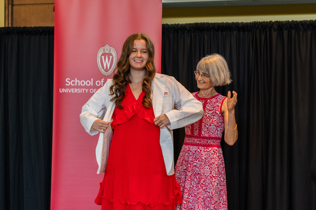 A student receives her white coat from Mara Kieser