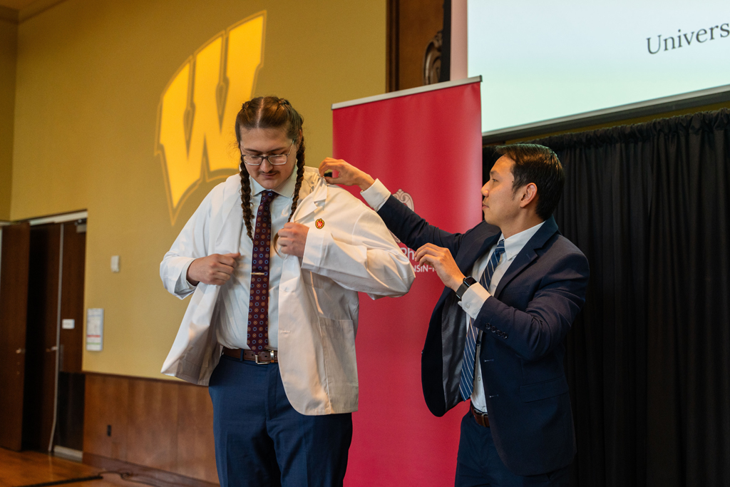 A student receives his white coat from Sean Lim