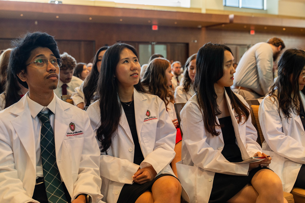 Students in white coats look upward