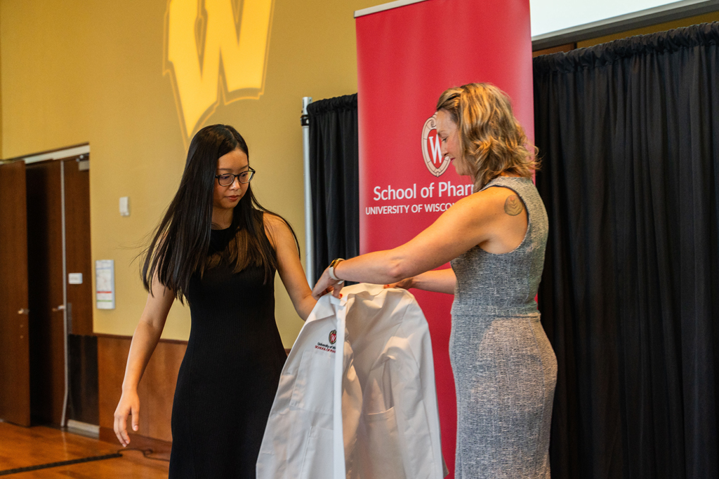 A student receives her white coat from Kate Rotzenberg