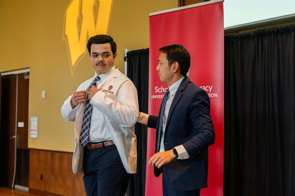 A student receives his white coat from Sean Lim